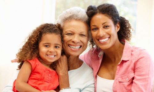 mother, daughter and granddaughter smile at the camera